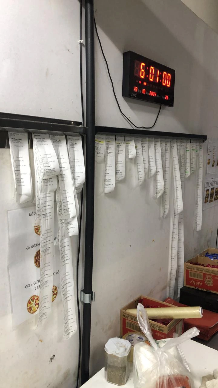 Painel cheio de comandas reais penduradas na operação de delivery do Igor