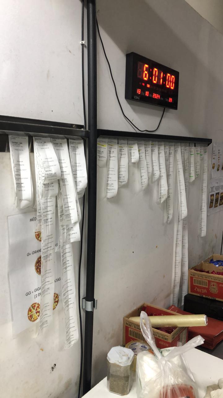 Painel cheio de comandas reais penduradas na operação de delivery do Igor
